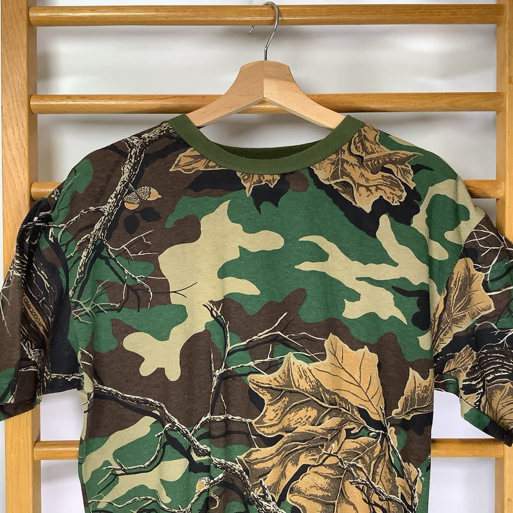 close up of a camo print shirt on a wooden hanger with a white background.