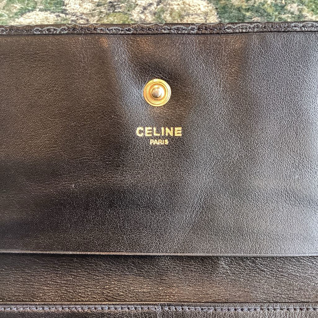 Black Celine wallet with gold logo on a textured surface
