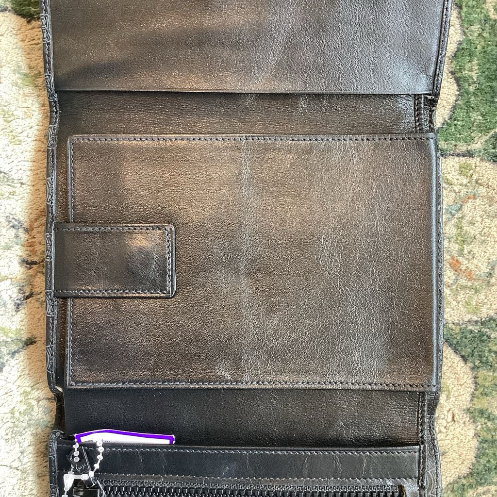 Brown leather wallet with visible wear on a textured surface
