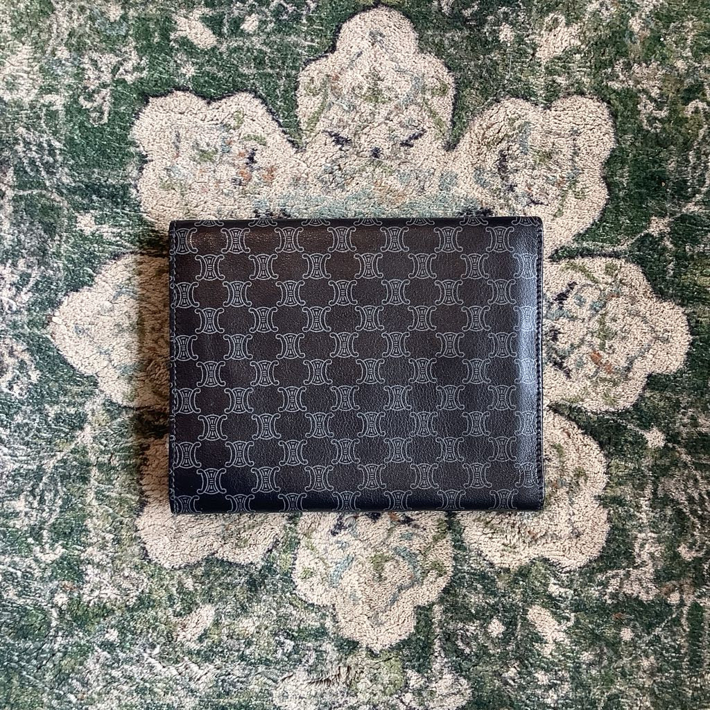 Black patterned wallet on a textured green surface