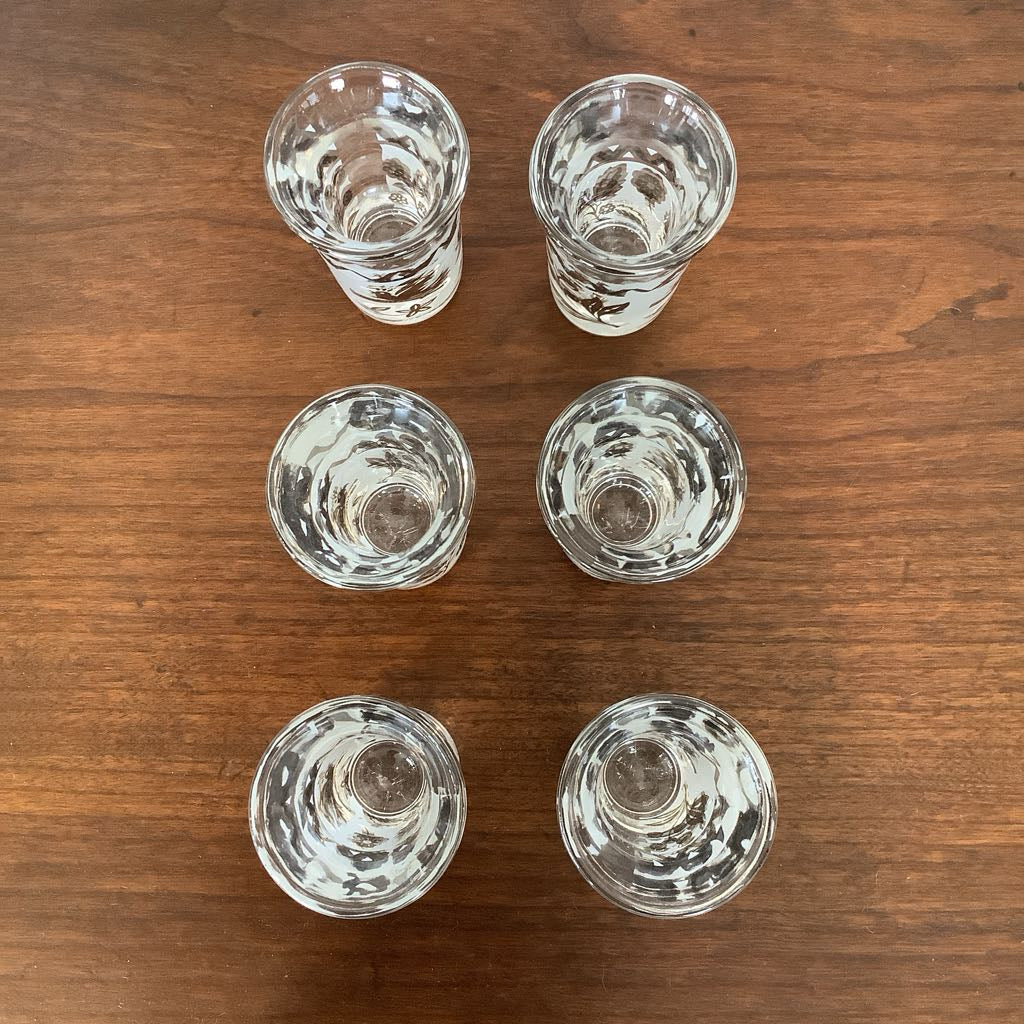 Six clear glass shot glasses on a wooden surface