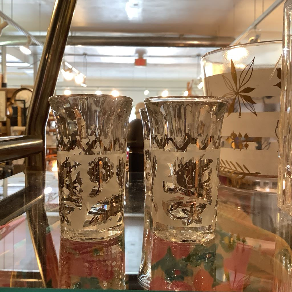 Two decorative glass tumblers with intricate designs on a reflective surface.