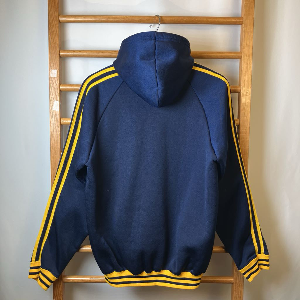 Navy blue hoodie with yellow stripes on a wooden rack against a light wall.