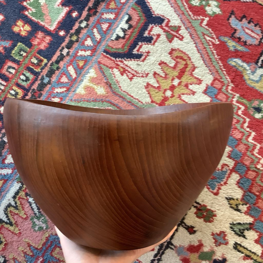Wooden bowl held in front of a colorful patterned rug