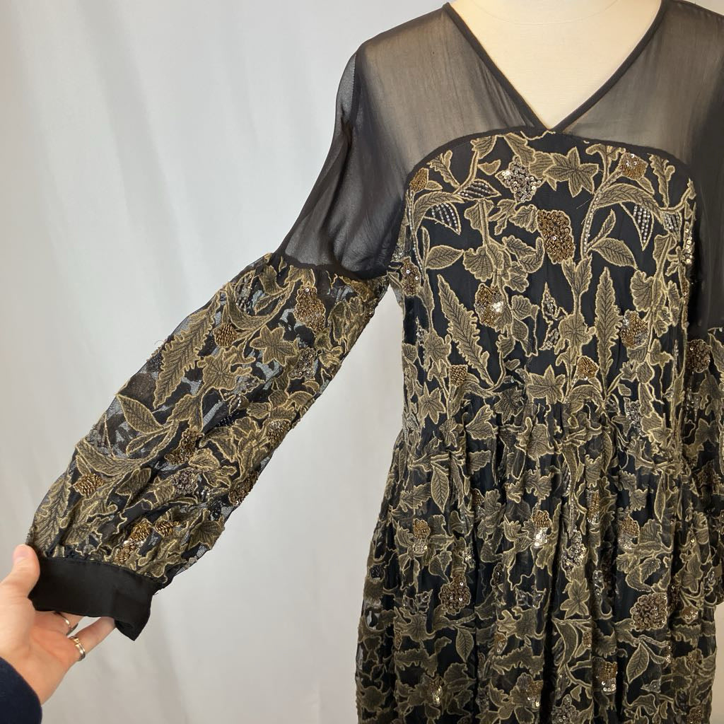 Black dress with gold floral pattern on a plain background