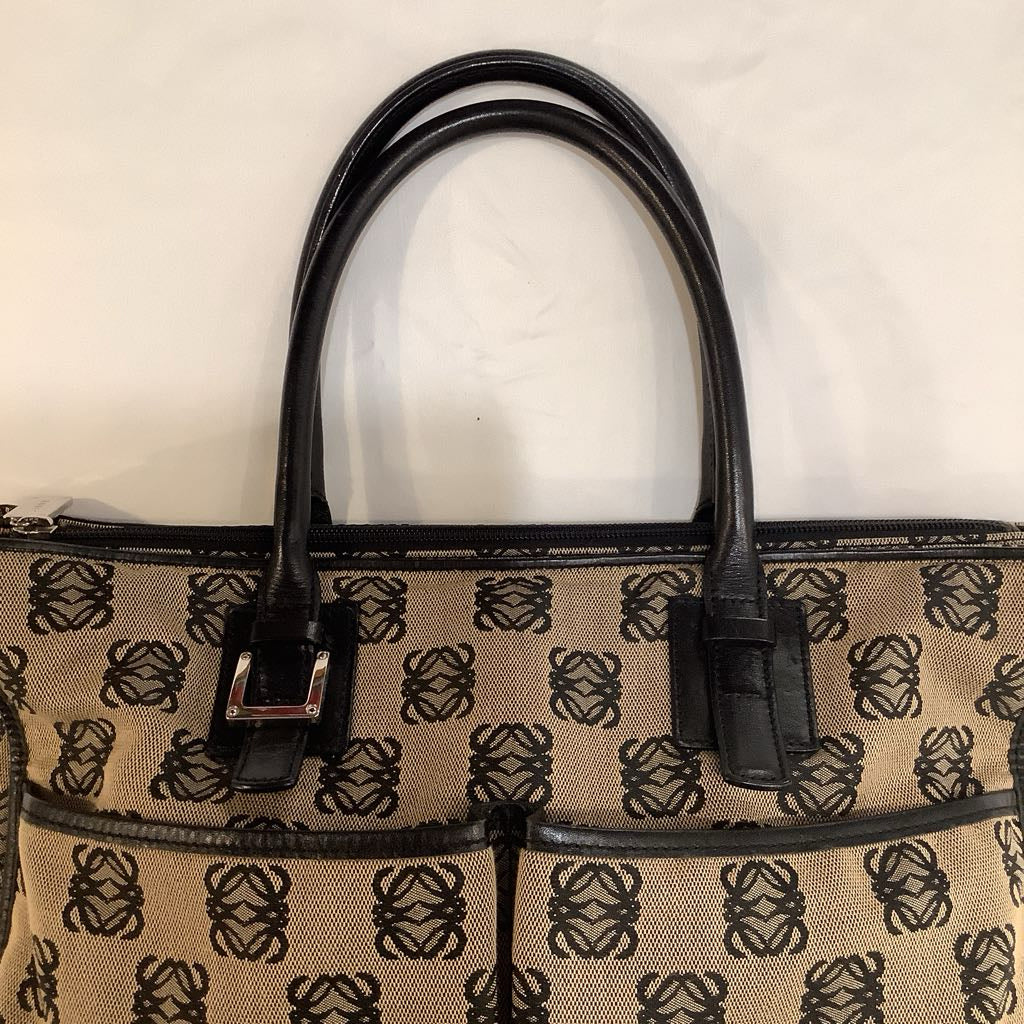 Beige handbag with black pattern and handles on a beige background