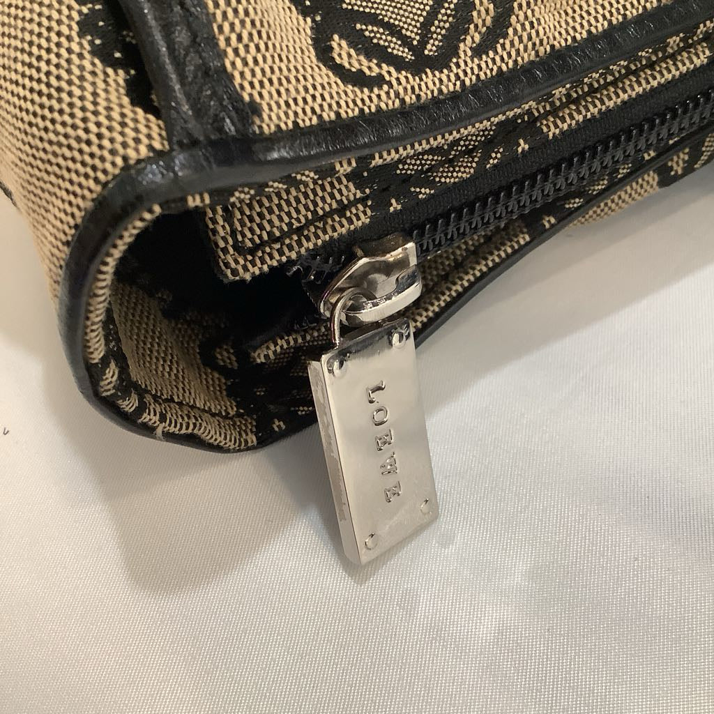Close-up of a textured pouch with a zipper and visible brand tag on a light background