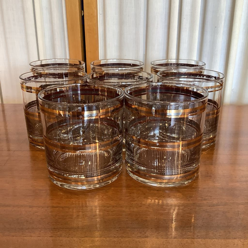 Set of clear glass tumblers with gold rim on a wooden table