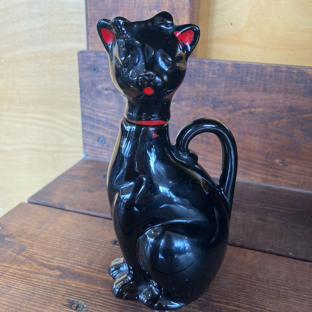 Black cat-shaped decanter on a wooden surface