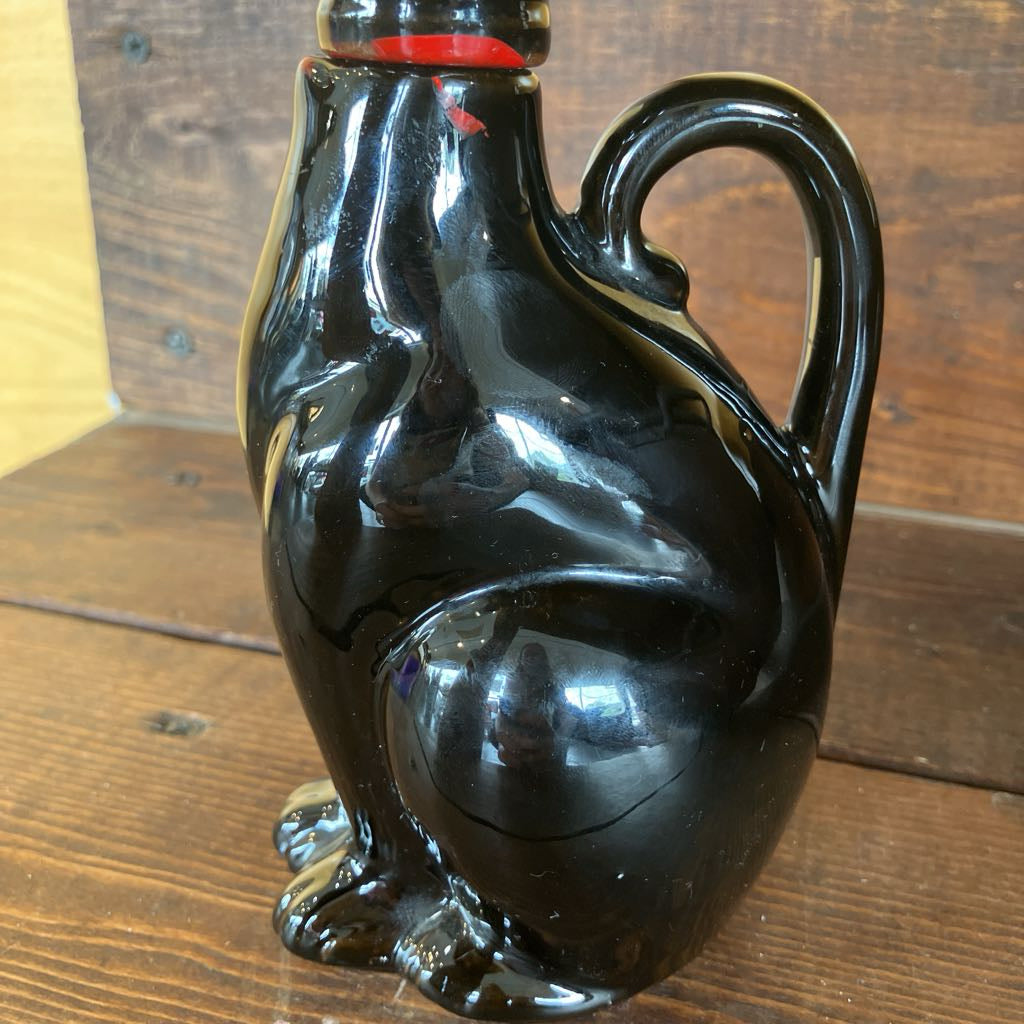 Black ceramic jug shaped like a bear on a wooden surface