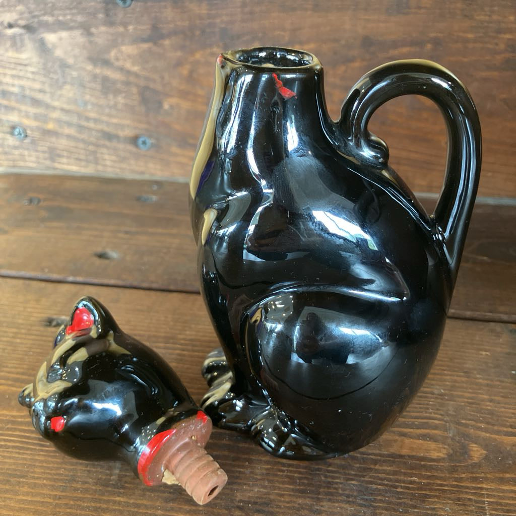 Black ceramic wine decanter with a stopper on a wooden surface