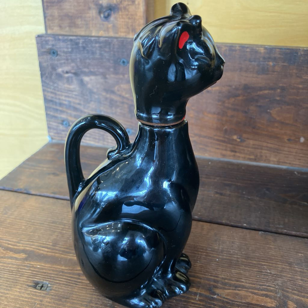 Black cat-shaped ceramic jar on a wooden surface