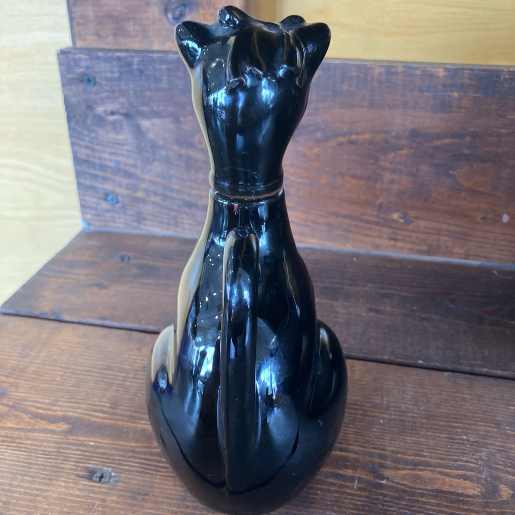 Black cat-shaped object on a wooden surface
