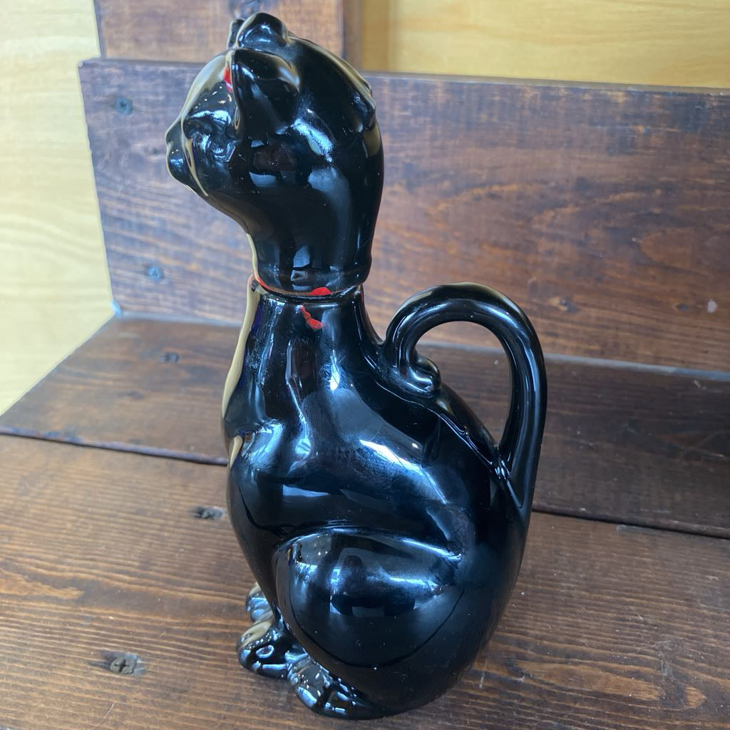 Black cat-shaped ceramic jar on a wooden surface