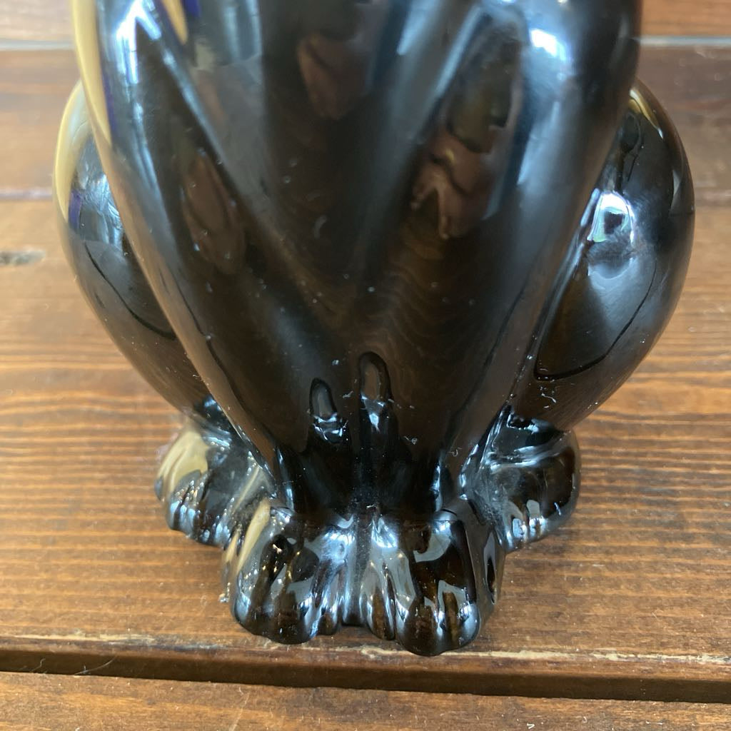 Black ceramic sculpture of a panther on a wooden surface