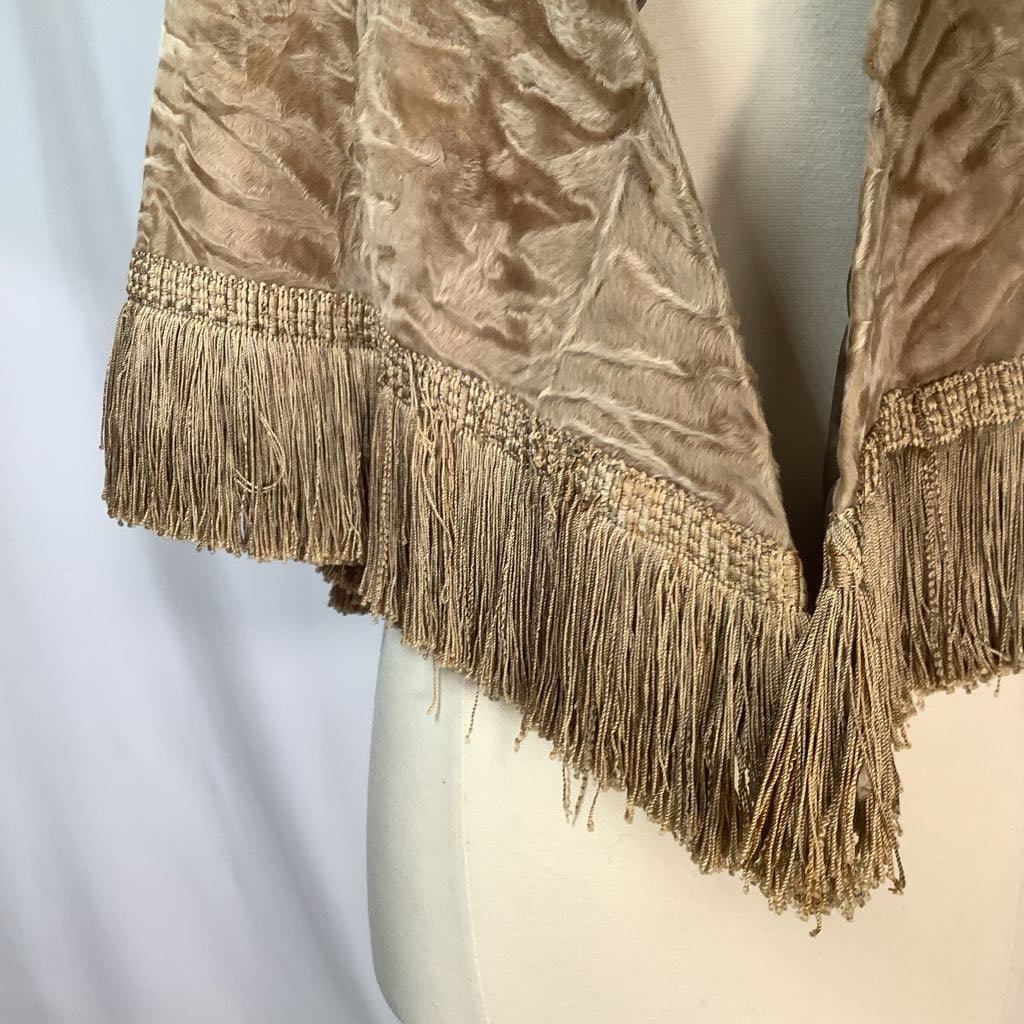 Textured fabric with gold fringe on a mannequin against a white background