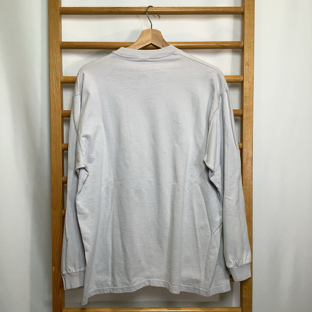 Light gray long-sleeve shirt on a wooden hanger against a white wall