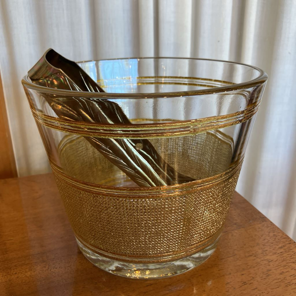 Glass ice bucket with gold design on a wooden surface