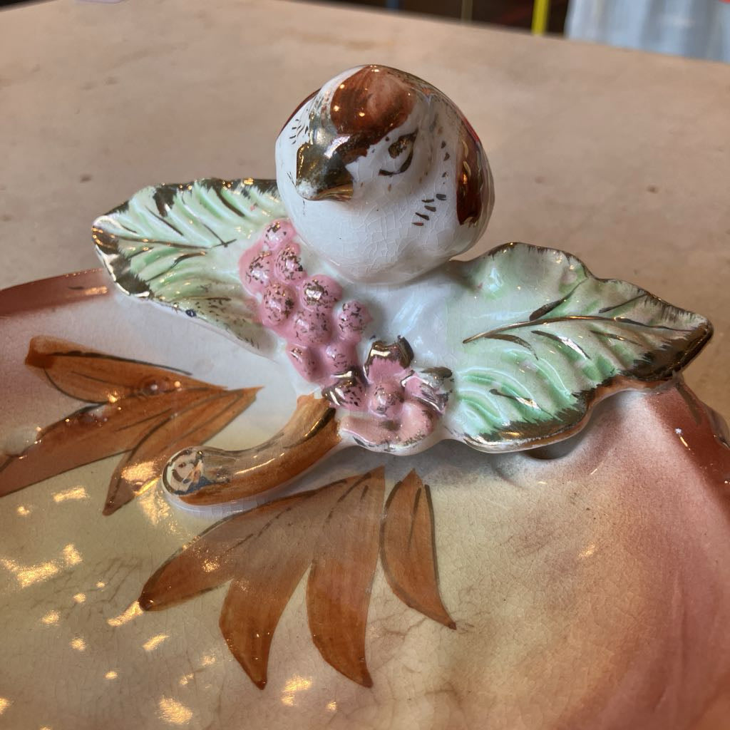 Up close of decorative ceramic bird on leaves