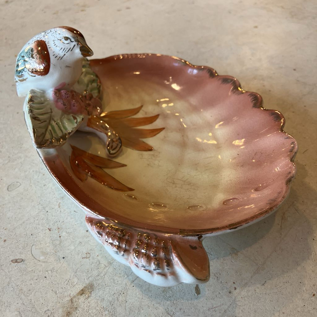 Decorative ceramic dish with a bird and floral design on a shell shaped base