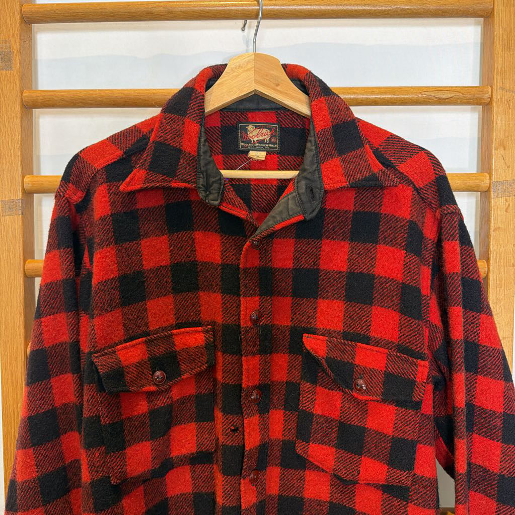 A red plaid long sleeved shirt on a wooden rack.