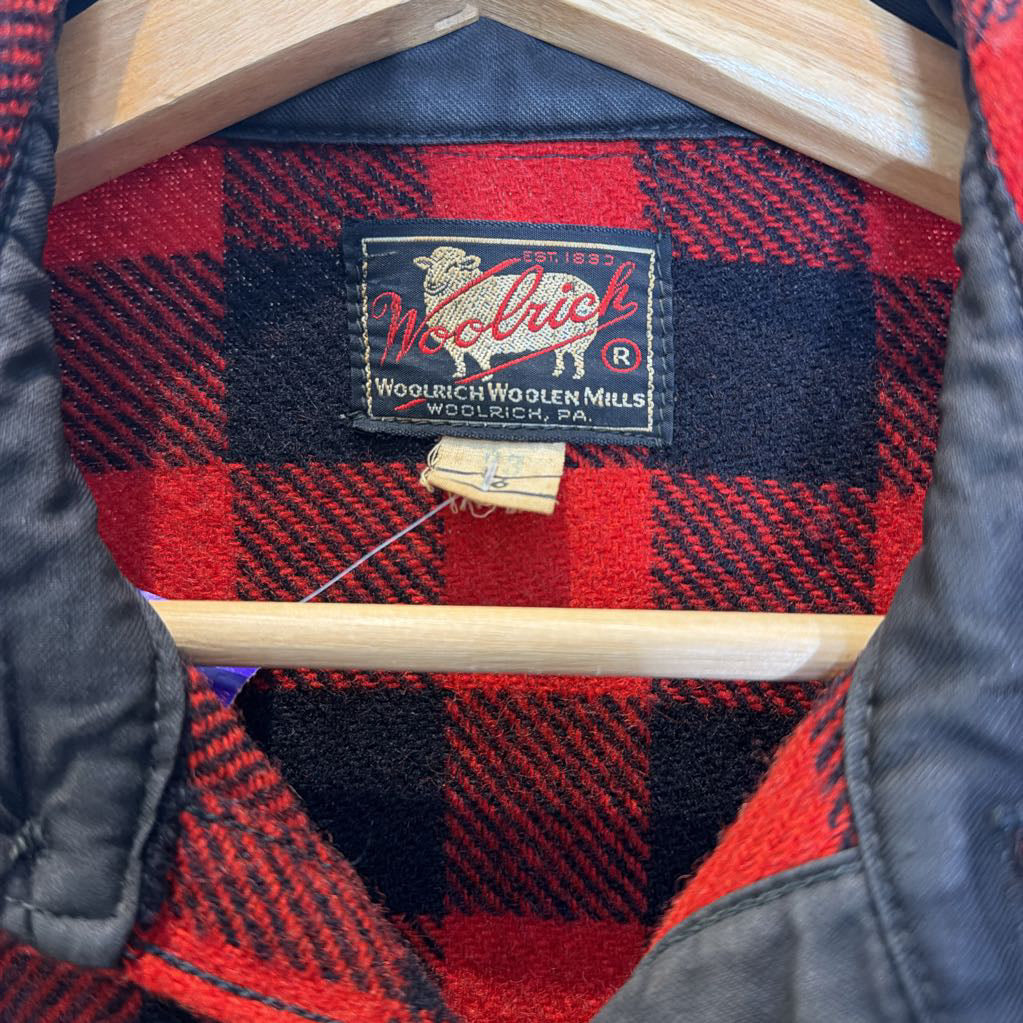 A red plaid long sleeved shirt on a wooden rack.