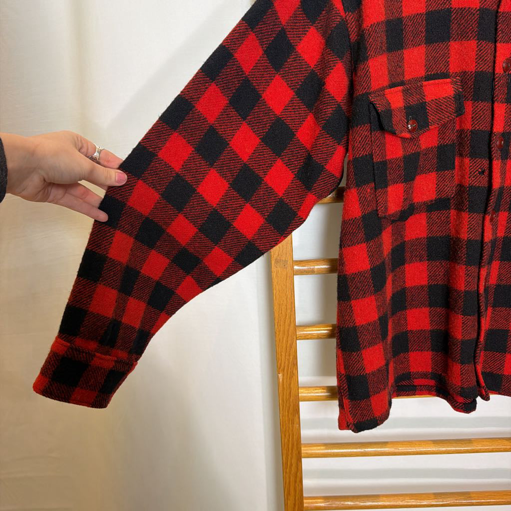 A red plaid long sleeved shirt on a wooden rack.