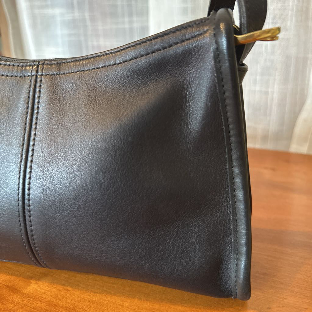 Black leather handbag on a wooden surface with a blurred background