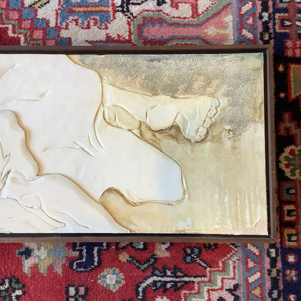 Close-up of a classical sculpture on a textured surface with a colorful patterned rug in the background