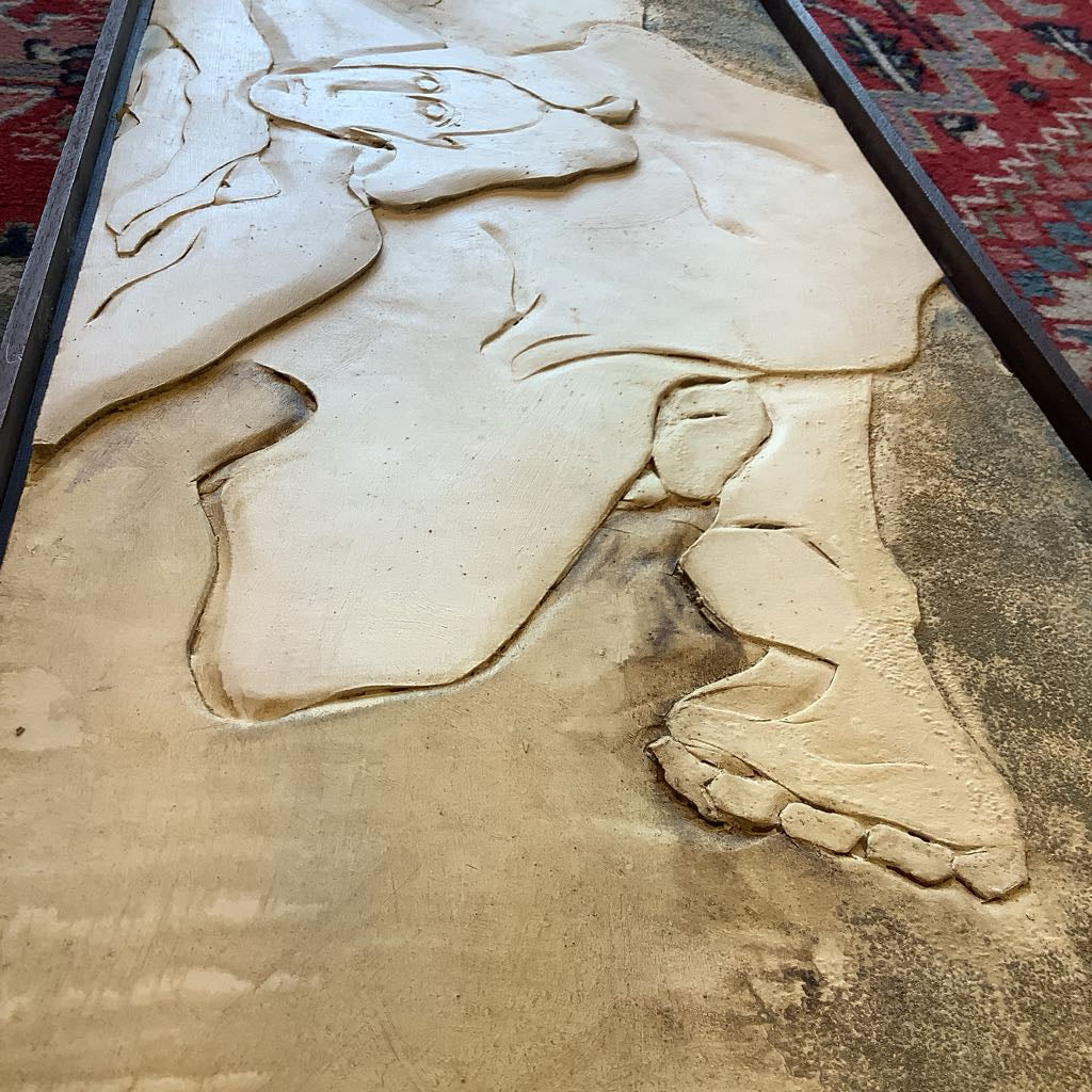 Carved relief of a person's feet on a textured surface