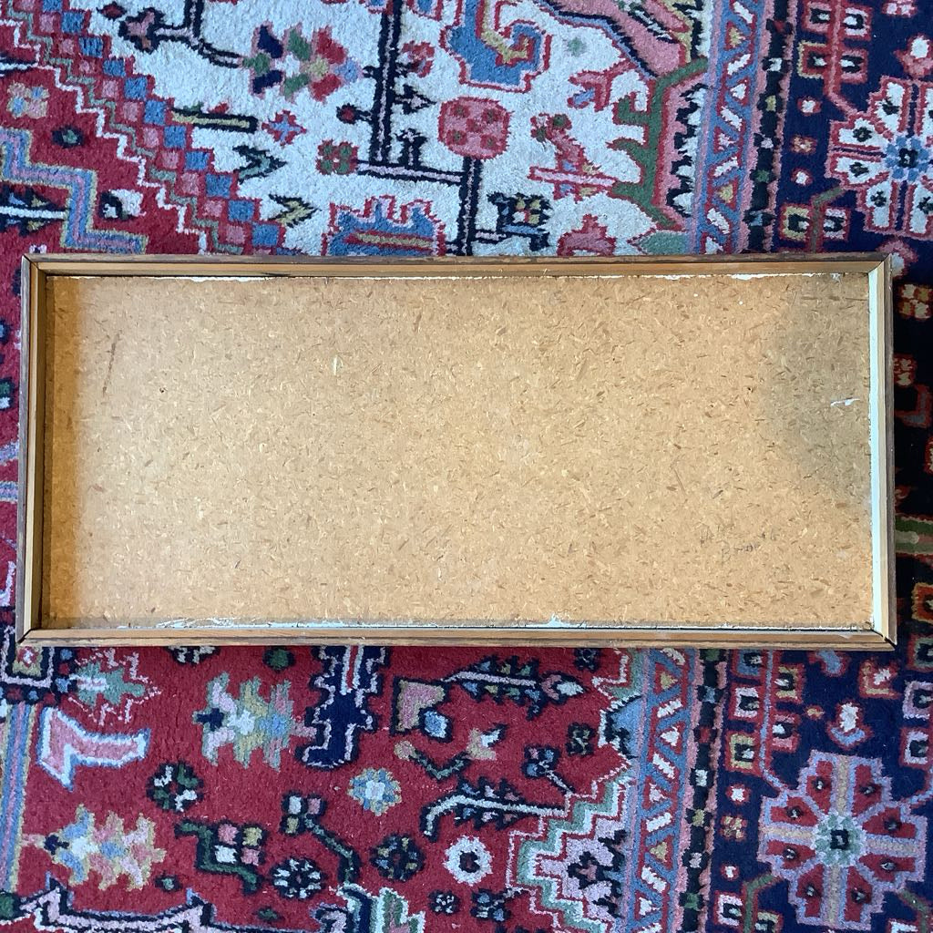 Back of wall art in a wooden picture frame on a patterned rug