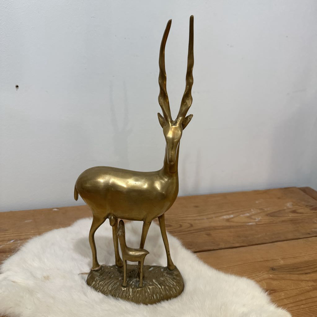 Brass antelope figurine on a white fur surface with a wooden base.