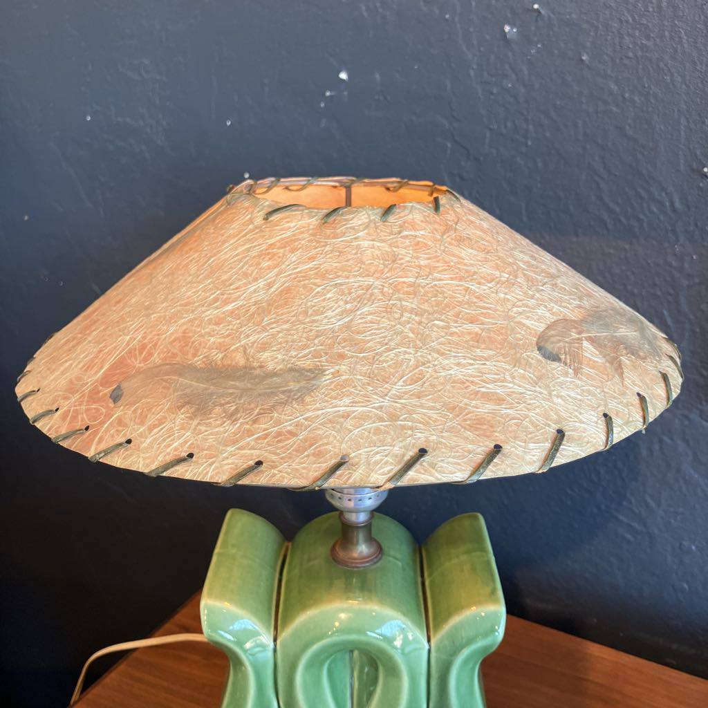 Fiberglass lamp shade on a green lamp base with black background