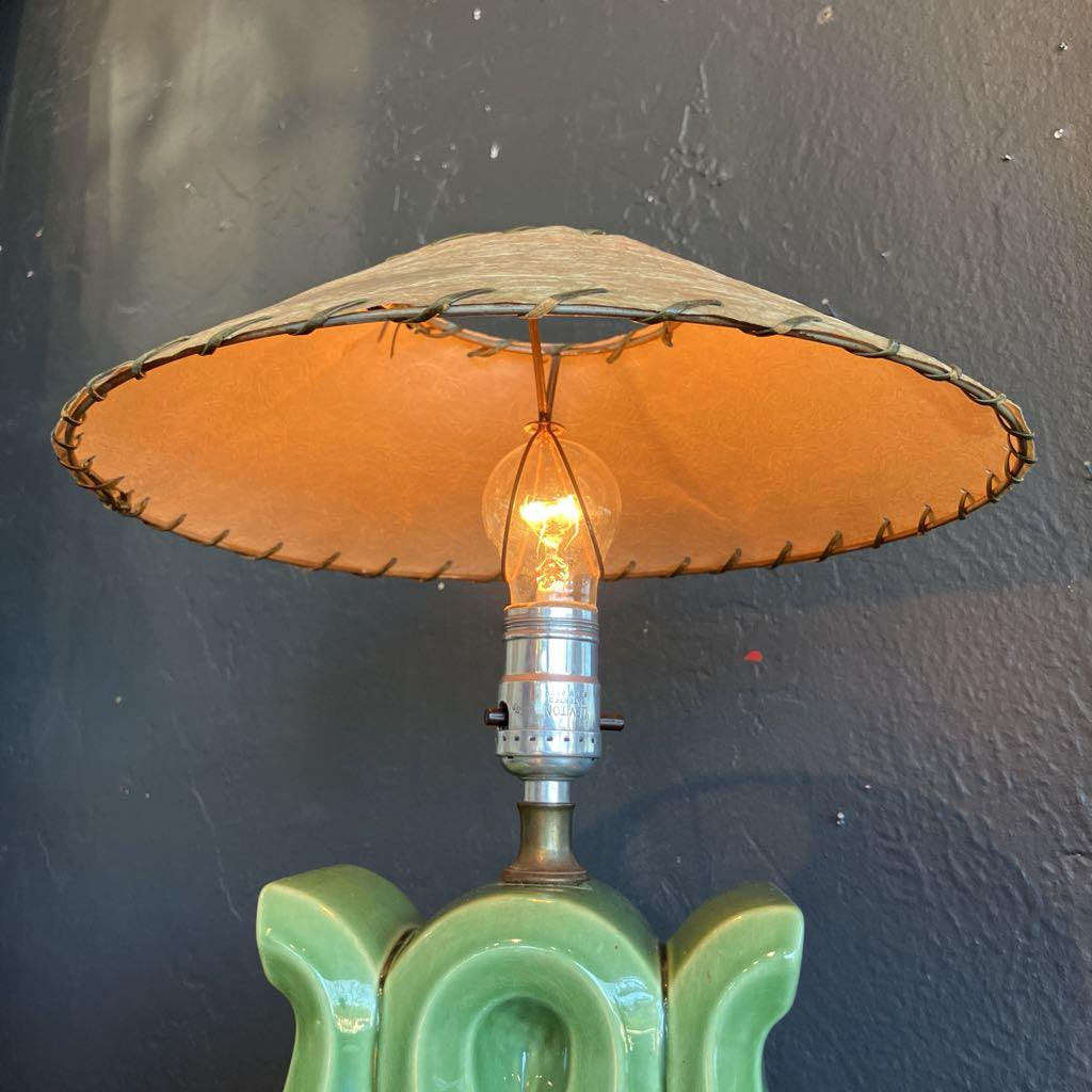 Brown fiberglass lamp shade on a green lamp base and with black background