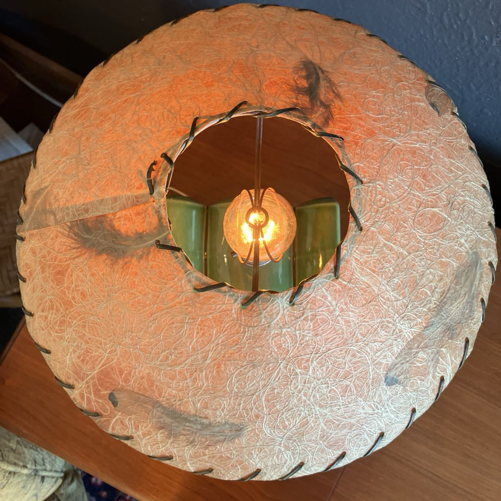 Brown fiberglass lamp shade on a wooden surface and with black background
