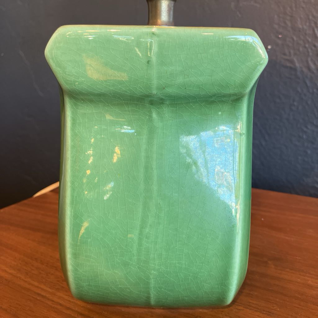 Green lamp base on a wooden surface and with black background