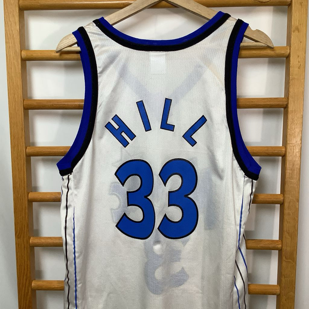 White basketball jersey with blue lettering and numbers, featuring the name 'HILL' and number '33', hanging on a wooden rack.