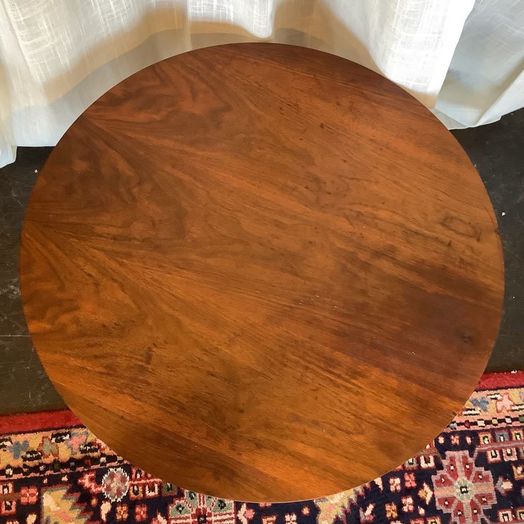 Round wooden table with a textured surface on a patterned rug.