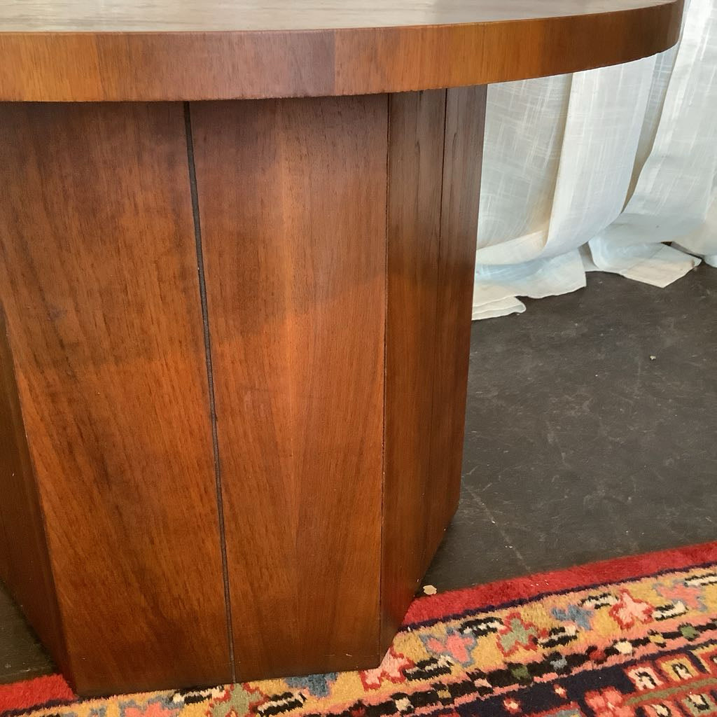 Wooden end table with a patterned rug and white curtains in the background