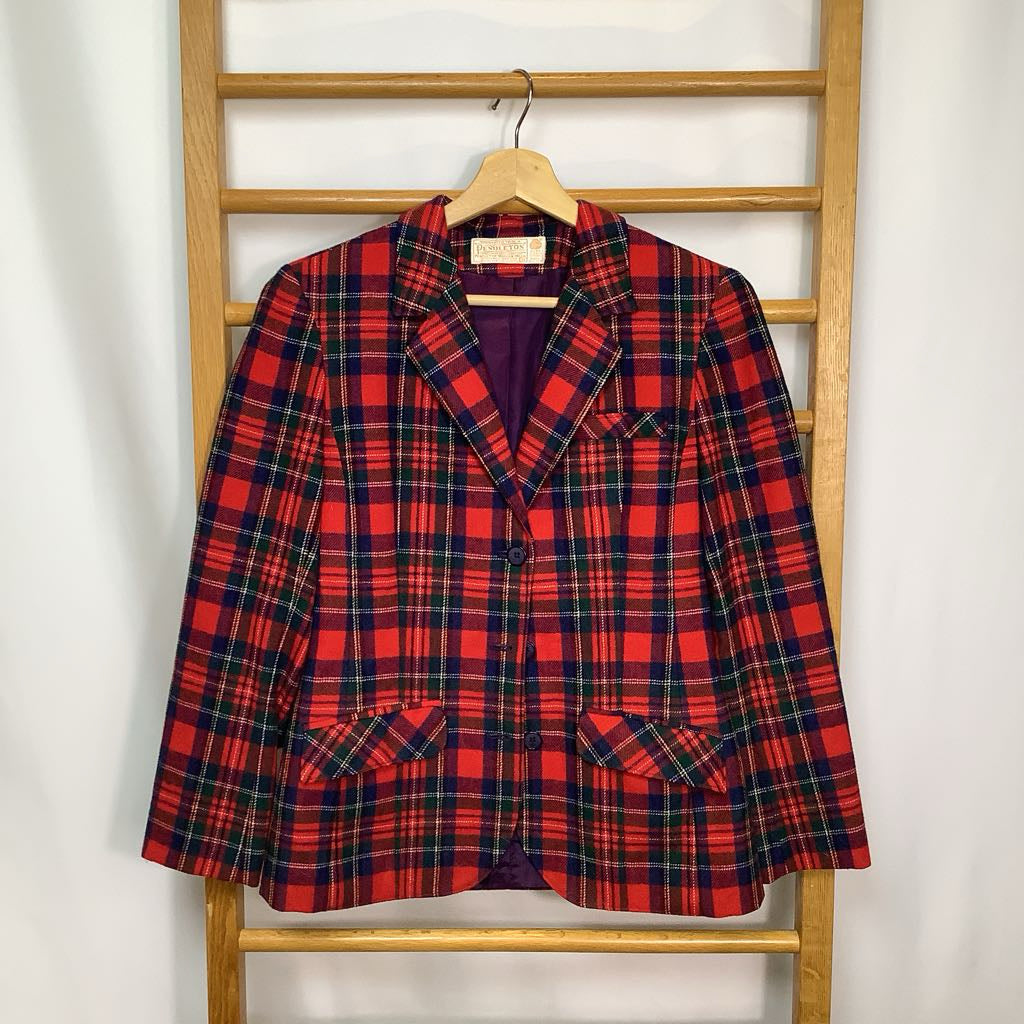 Red and blue plaid blazer on a wooden hanger against a white wall.