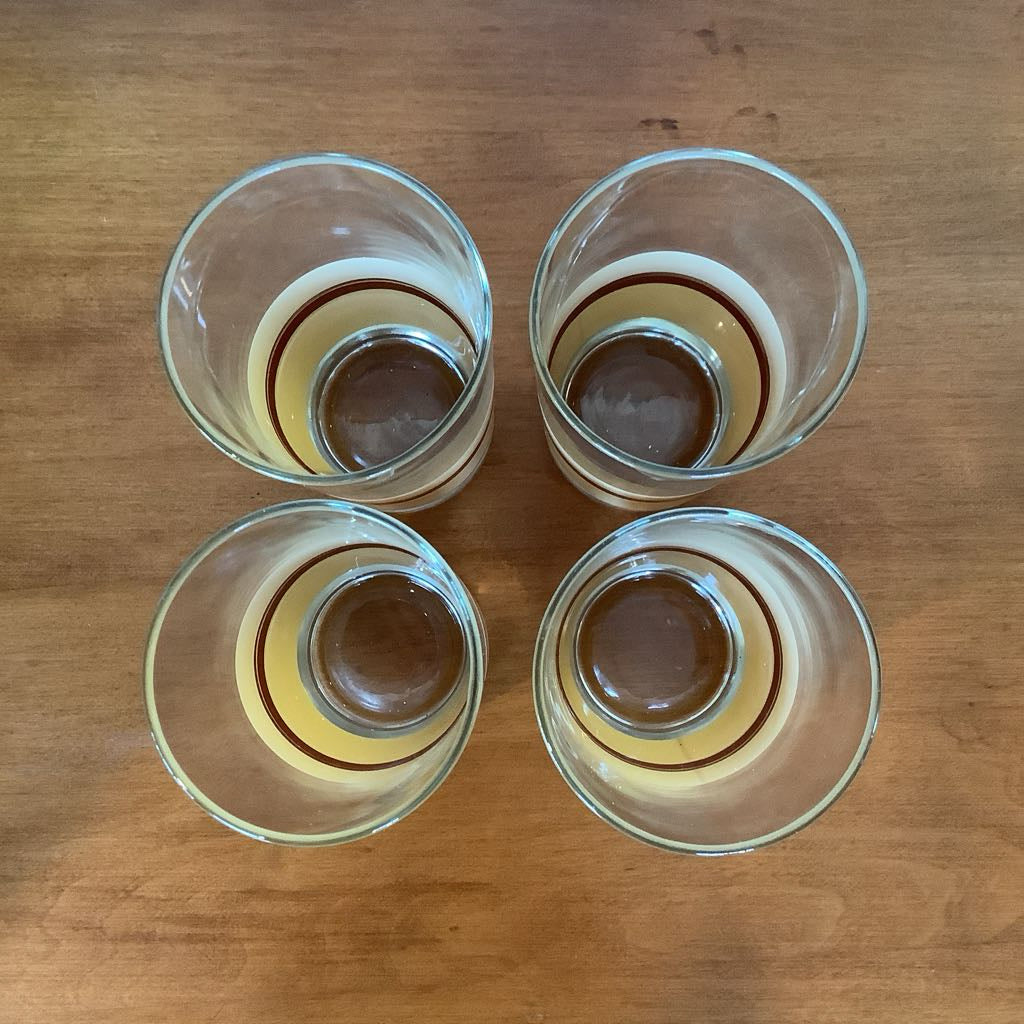 Four clear glass tumblers on a wooden surface