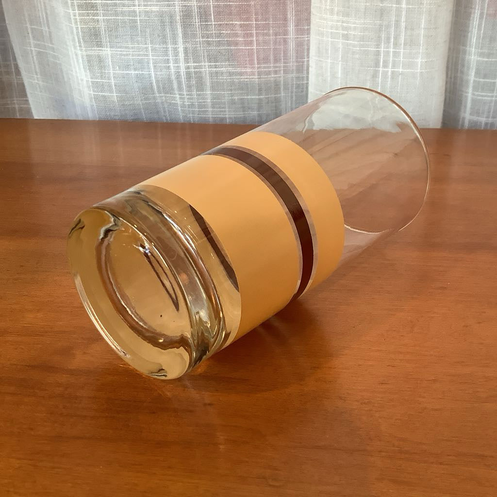 Clear glass container with beige and burgundy base on a wooden surface