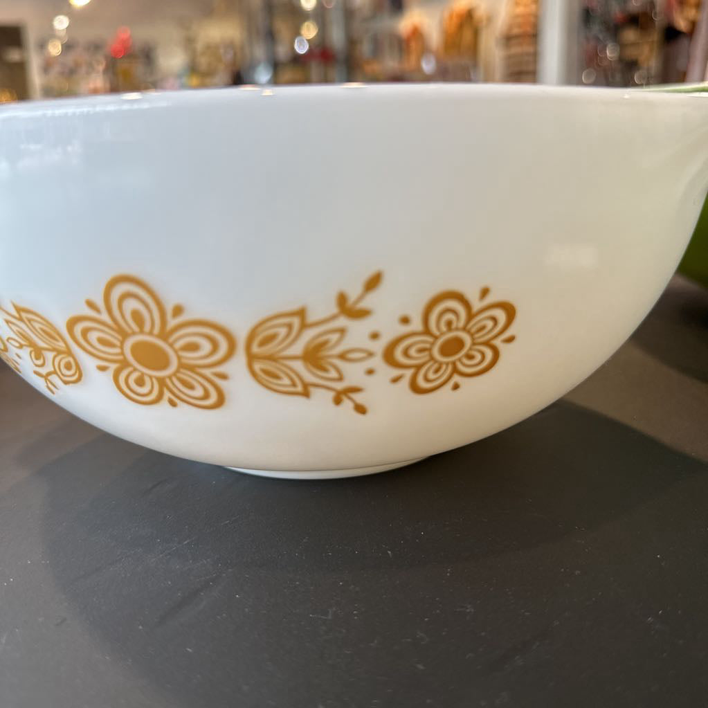 White bowl with gold floral pattern on a reflective surface