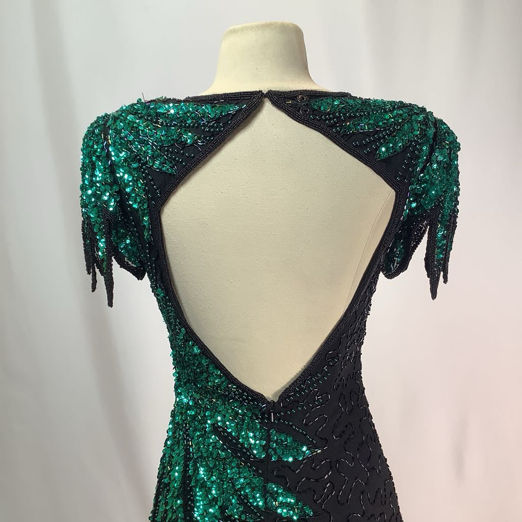 Green and black beaded dress on a mannequin against a plain background