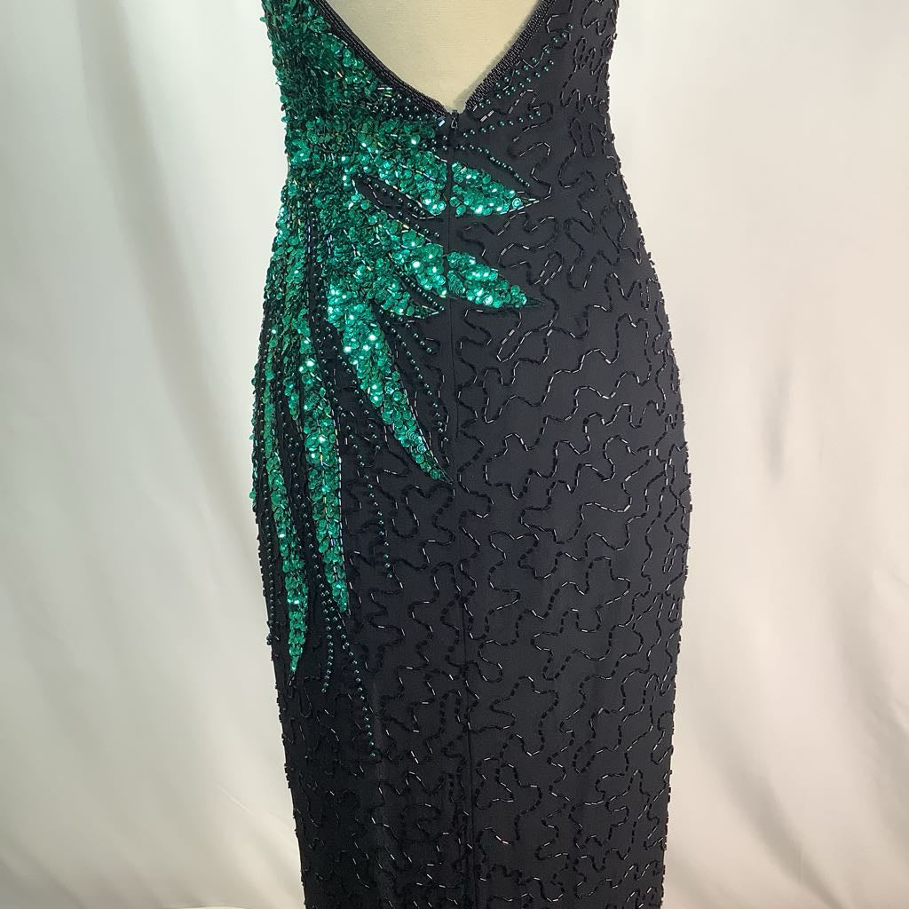 Black evening gown with green sequin detailing on a white background