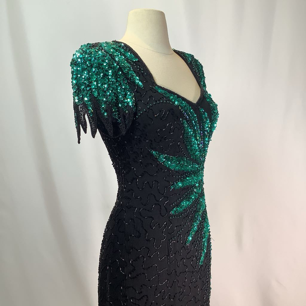 Black dress with green sequin embellishments on a mannequin against a white background