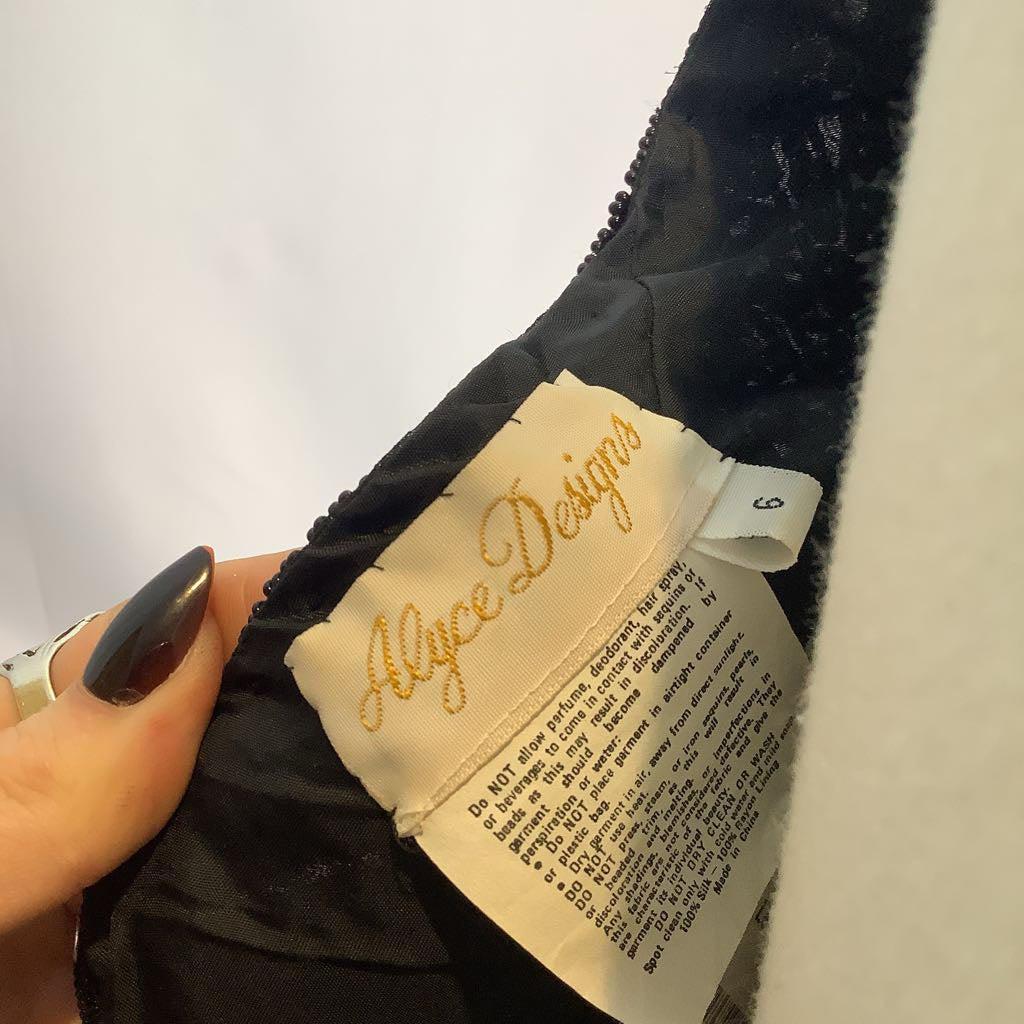 Close-up of a label on a black garment with 'Allyce Designs' branding.