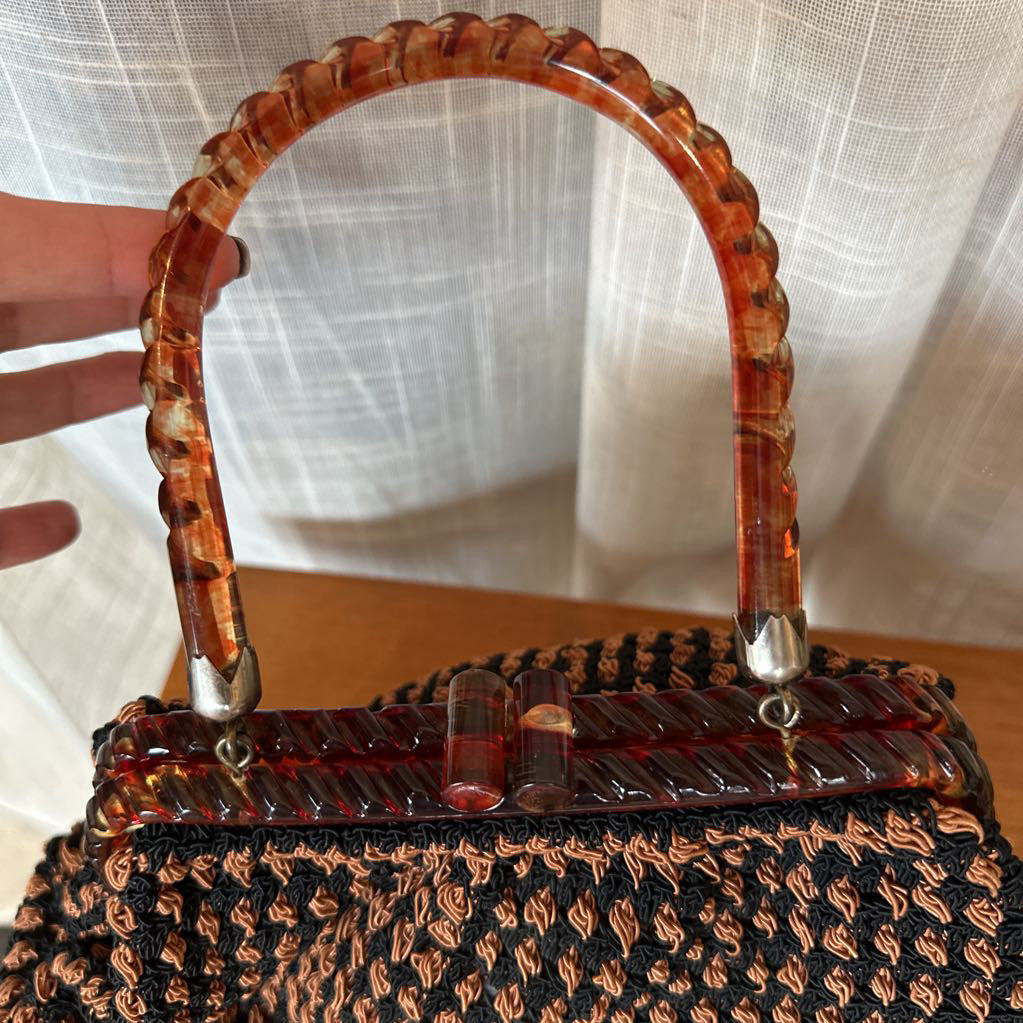 Handbag with tortoiseshell handle against a neutral background