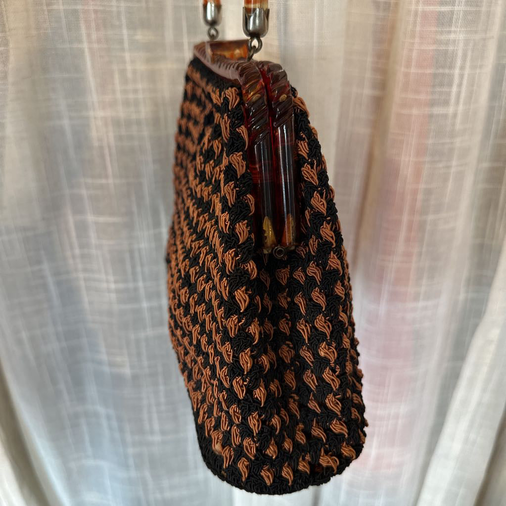 Black and brown patterned handbag with a chain strap on a light fabric background