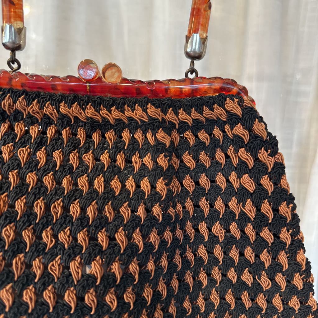 Vintage handbag with black and orange patterned body and tortoiseshell handle.